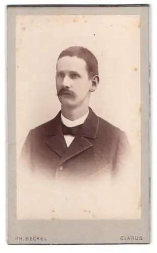 Fotografie Ph. Beckel, Glarus, bei der Kirche, Portrait Herr im Anzug mit Fliege und Walrossbart