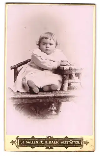 Fotografie C. H. Baer, St. Gallen, Portrait kleines Mädchen im weissen Kleid sitzt auf einem Tisch