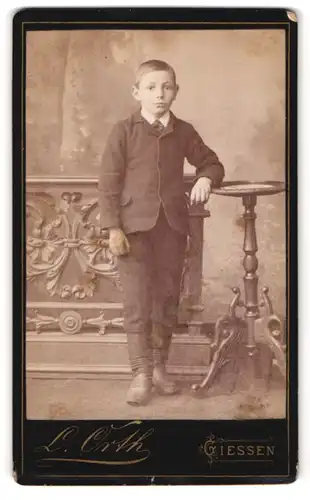 Fotografie L. Orth, Giessen, Neue Bäue 11, Portrait kleiner Junge im Anzug steht im Atelier