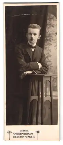 Fotografie Georg Haltermann, Eckernförde, Portrait charmanter junger Mann im Anzug am Tisch lehnend