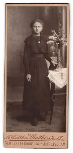 Fotografie M. Walther, Seifhennersdorf i. Sa., Portrait hübsches Fräulein im Kleid am Tisch stehend