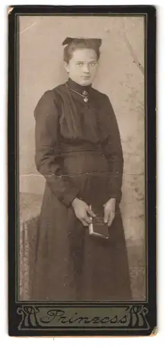 Fotografie Atelier Prinzess, Ort unbekannt, Portrait dunkelhaariges Fräulein mit Haarschleife und Buch in der Hand