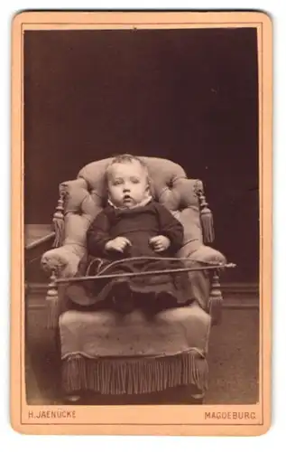 Fotografie H. Jaenücke, Magdeburg, Kaiserstr. 94, Kleinkind mit Reitgerte im Sessel sitzend