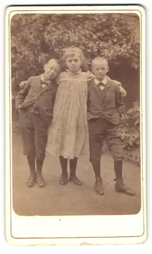 Fotografie Fotograf und Ort unbekannt, Portrait Schwester im Kleid mit zwei Brüdern in Anzügen mit Fliege