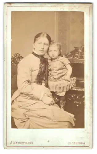 Fotografie J. Mackeprang, Oldenburg, Portrait Mutter mim Kleid mit kleiner Tochter im karierten Kleid