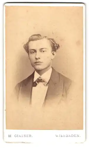 Fotografie H. Glaeser, Wiesbaden, Taunusstr. 19, Portrait junger Mann im Anzug mit Fliege und Locken