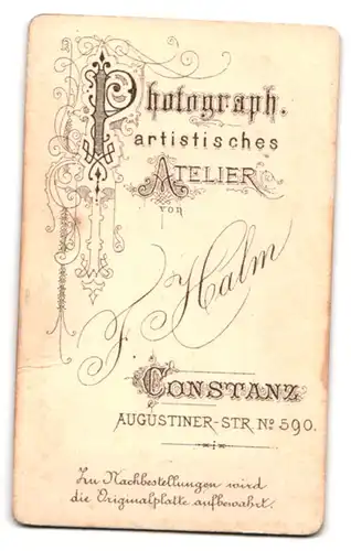 Fotografie F. Halm, Constanz, Augustiner-Str. 590, Portrait kleines Mädchen im karierten Kleid sitzt auf einem Tisch