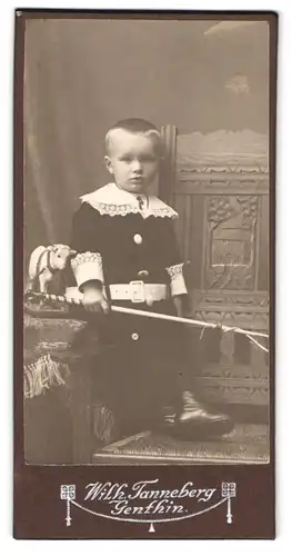 Fotografie Wilh. Tanneberg, Genthin, Portrait Junge im Anzug mit Spitzenkragen und Spielzeugkuh