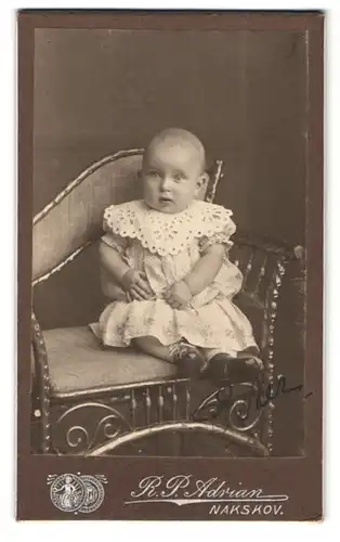 Fotografie R. P. Adrian, Nakskov, Portrait Kleinkind im Kleid mit Spitzenkragen auf einem Stuhl