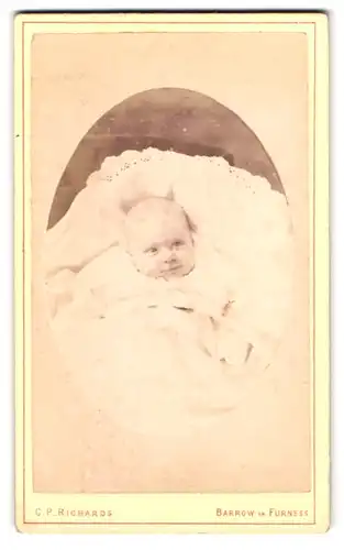 Fotografie C.P. Richards, Barrow-in-Furness, glückliches Baby in Wiege liegend