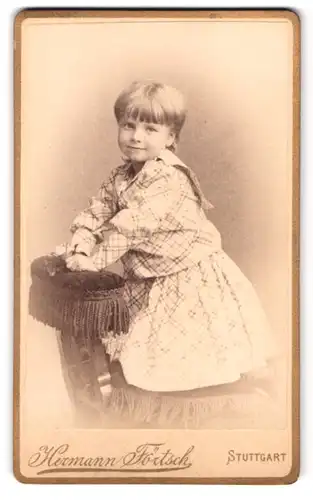 Fotografie Hermann Förtsch, Stuttgart, Schellingstr. 13, Portrait Mädchen im karierten Kleid auf einen Stuhl gestützt