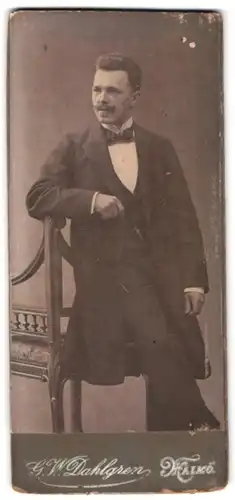Fotografie G. W. Dahlgren, Malmö, Portrait Herr im Anzug mit Oberlippenbart lehnt an einem Stuhl