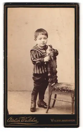 Fotografie Atelier Walther, Wilhelmshaven, Roon-Str. 75, Portrait kleiner Junge im gestreiften Oberteil mit Puppe