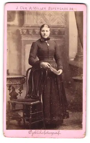 Fotografie J. Chr. A. Möller, Kjöbenhavn, Ostergade 58, Portrait junge Frau im Kleid mit Haube und Buch in der Hand