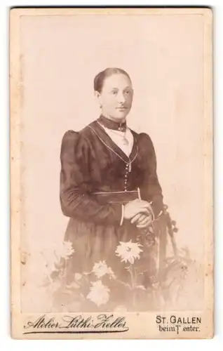 Fotografie Lüthi-Zeller, St. Gallen, beim Theater, Portrait junge Frau im Kleid mit Brosche steht vor Blumen
