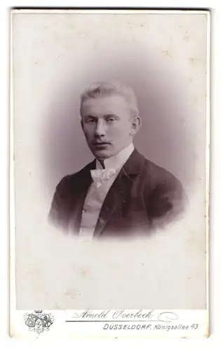 Fotografie Arnold Overbeck, Düsseldorf, Königsallee 43, Portrait blonder Mann im Anzug mit weisser Fliege