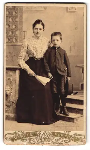 Fotografie Fotograf und Ort unbekannt, Portrait Mutter in karierter Bluse mit Fächer und Sohn im Anzug mit Hut