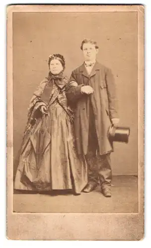 Fotografie Fotograf und Ort unbekannt, Portrait ältere Dame im seidenen Kleid nebst ihrem Sohn im Anzug mit Zylinder
