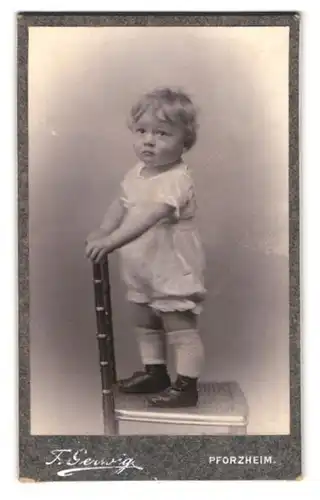 Fotografie F. Gerwig, Pforzheim, Westl. Carl Friedrichstr. 40, Portrait kleiner Junge im weissen Leibchen steht auf Stuhl