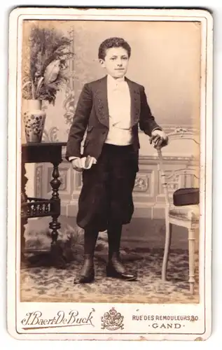 Fotografie J. Baert De Buck, Gand, Rue des Remouleurs 30, Portrait Junge im Anzug mit Locken und Knickerbockern