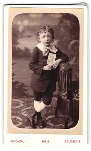Fotografie Simoneau & Bourgeois, Paris, 50, Rue Fabert, 50, Portrait modisch gekleideter Junge mit Kärtchen