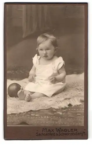 Fotografie Max Wagler, Sachsenfeld i. S., Baby mit Ball auf Felldecke sitzend