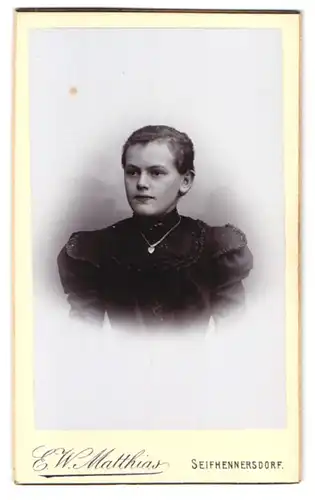 Fotografie E. W. Matthias, Seifhennersdorf i. S., Portrait junge Frau im schwarzen Kleid mit Herzanhänger an Halskette