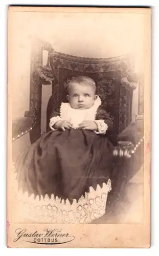 Fotografie Gustav Werner, Cottbus, Kaiser-Friedrichstrasse 86, Baby im Taufkleid auf einem Sessel