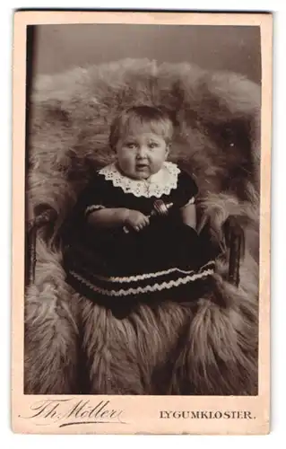 Fotografie Th. Möller, Lygumkloster, Portrait dickers Kleinkind im Kleid mit Rassel in der Hand