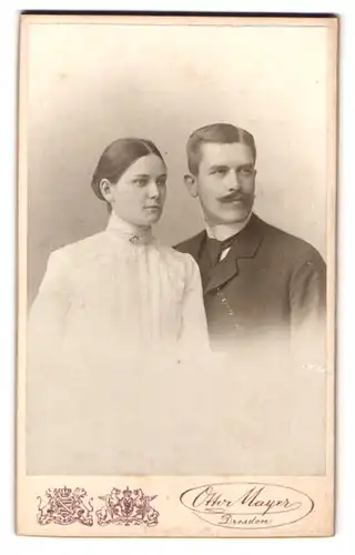 Fotografie Otto Mayer, Dresden, Pragerstr. 38, Portrait Eheleute im Anzug mit Walrossbart und weissen Kleid mit Brosche