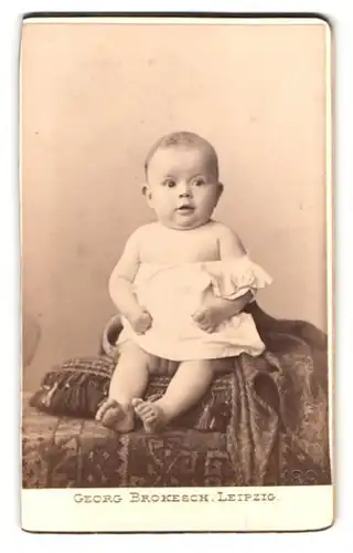 Fotografie Georg Brokesch, Leipzig, Zeitzerstr. 2, Portrait kleines Baby im Leibchen sitzt auf einem Kissen