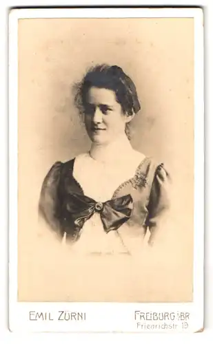 Fotografie Emil Zürni, Freiburg i. Br., Friedrichstr. 19, Portrait Dame im Kleid mit grosser Schleife und Locken