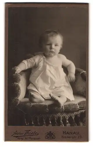 Fotografie Atelier Thiele, Hanau a. M., Kramerstr. 23, Portrait kleines Kind im weissen Kleid sitzt im Sessel
