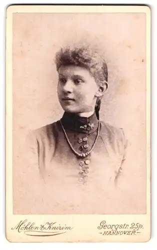 Fotografie Möhlen & Knirim, Hannover, Georgstr. 25, Portrait junges Mädchen im Kleid mit Perlenkette und Brosche, Locken