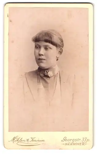 Fotografie Möhlen & Knirim, Hannover, Georgstr. 33, Portrait junge Frau im hellen Kleid mit Brosche und Pony