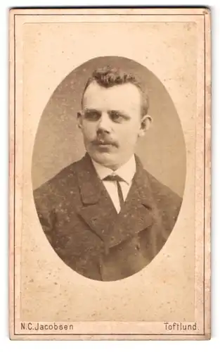 Fotografie N. C. Jacobsen, Toftlund, Portrait Mann im Anzug mit Segelohren und Oberlippenbart