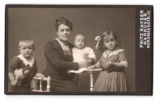 Fotografie Fritz Kayser, Hannover, Nordmannstr. 12, Portrait Mutter mit drei Kindern in Kleidern, Stofftier Hund