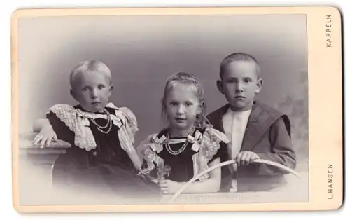 Fotografie L. Hansen, Kappeln, Portrait drei Kindern in Kleidern mit Schleifen und Junge im Anzug mit Reifen