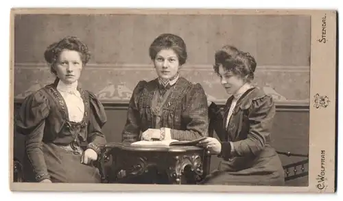 Fotografie C. Wolfram, Stendal, Portrait drei Damen in Biedermeierkleidern posieren am Tisch