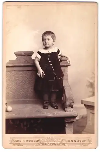 Fotografie Karl F. Wunder, Hannover, Friedrichstrasse, kleines Mädchen mit Kleid auf einer Bank stehend