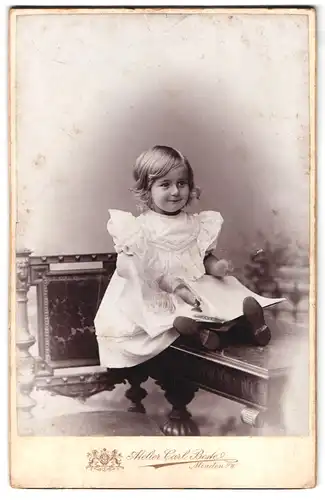 Fotografie Carl Bestel, Minden, kleines Mädchen mit weissem Kleid sitzt auf einem Tisch