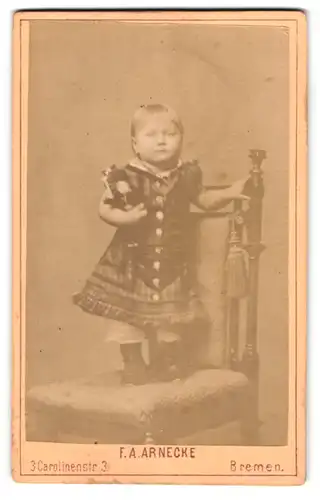 Fotografie F. A. Arnecke, Bremen, Carolinenstrasse 3, Portrait kleines Mädchen im Kleid mit Puppe