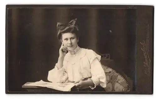 Fotografie R. Schwarzbach, Bitterfeld, Kaiserstrasse 14, hübsche Dame mit Haarschleife und aufgeschlagenem Fotoalbum