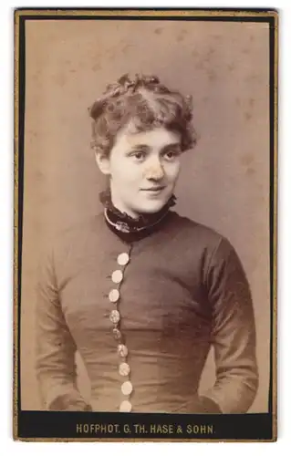 Fotografie G. Th. Hase & Sohn, Freiburg i. B., Karlsplatz 4, Portrait junge Frau im Kleid mit Locken schaut verschmitzt