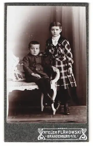 Fotografie Flakowski, Brandenburg a. H., Portrait Junge und Mädchen im karierten Kleid und Anzug, Kreuzkette