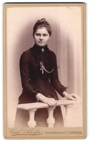 Fotografie Carl Schäfer, Elberfeld, Kipdorfstr. 57, Portrait junge Frau im schwarzen taillierten Kleid mit Brosche