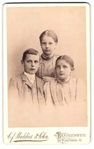 Fotografie C. F. Beddies & Sohn, Braunschweig, Kuhstrasse 10, Portrait zwei Mädchen und Junge in Kleidern und Anzug