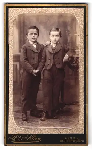 Fotografie H. O. Klein, Lahr i. Baden, Portrait zwei Knaben in karierten Anzügen halten Händchen im Atelier