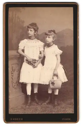 Fotografie N. Kneer, Hamm a. Lippe, Markt 14, Portrait zwei Mädchen in weissen Kleidern vor einer Studiokulisse