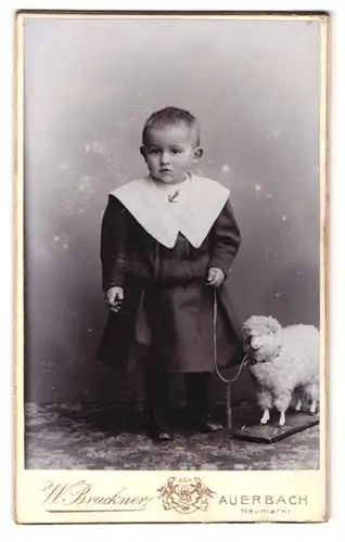 Fotografie W. Bruckner, Auerbach, Neumarkt, Portrait kleines Mädchen im Matrosenkleid mit Spielzeugschaf